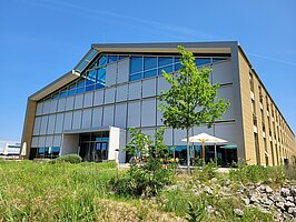 Das Alnatura-Gebäude vor blauem Himmel und Wiese.