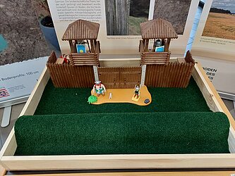 eine flache Kiste aaausgelegt mit Rasenteppich und einem römischen Wachturm, sowie Asterix und Obelix